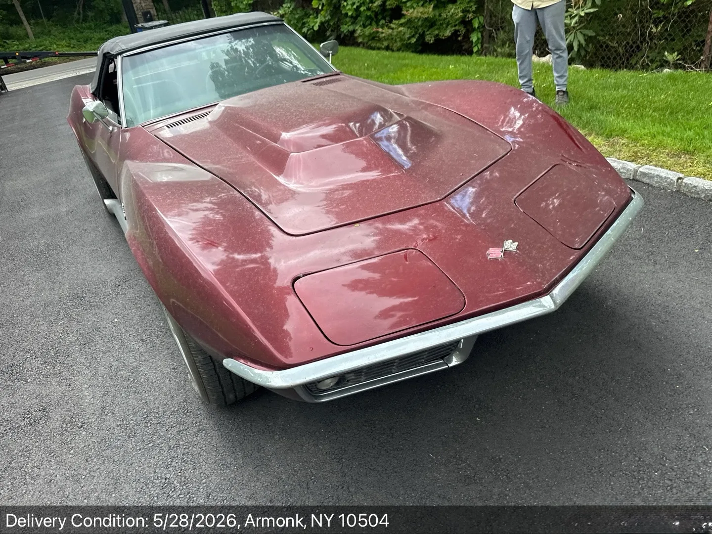 Front view of a classic maroon C3 Corvette Stingray convertible with chrome bumpers after delivery in Armonk, NY