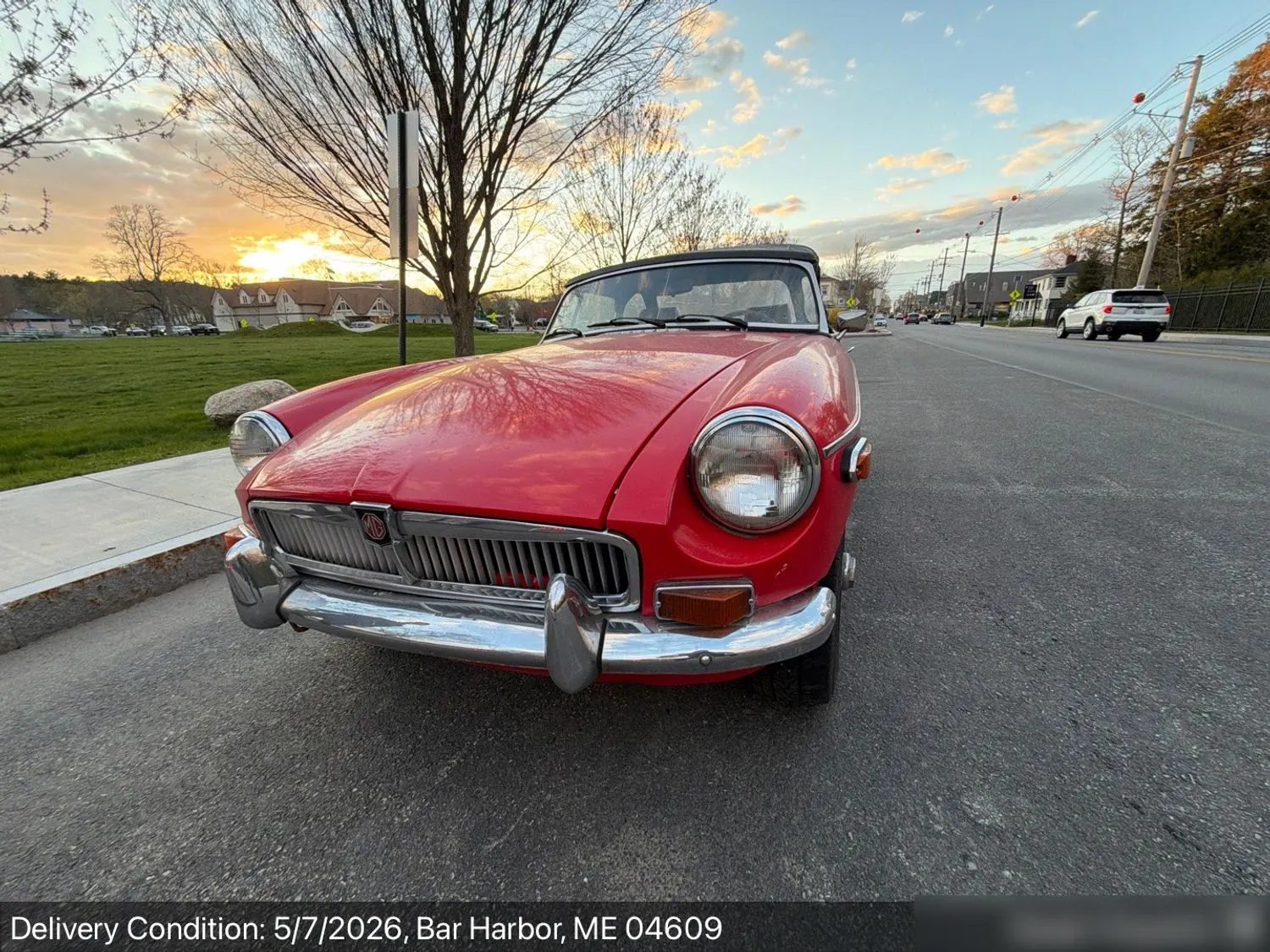 The same red MGB roadster at delivery at sunset in Bar Harbor, Maine, top up, paint intact