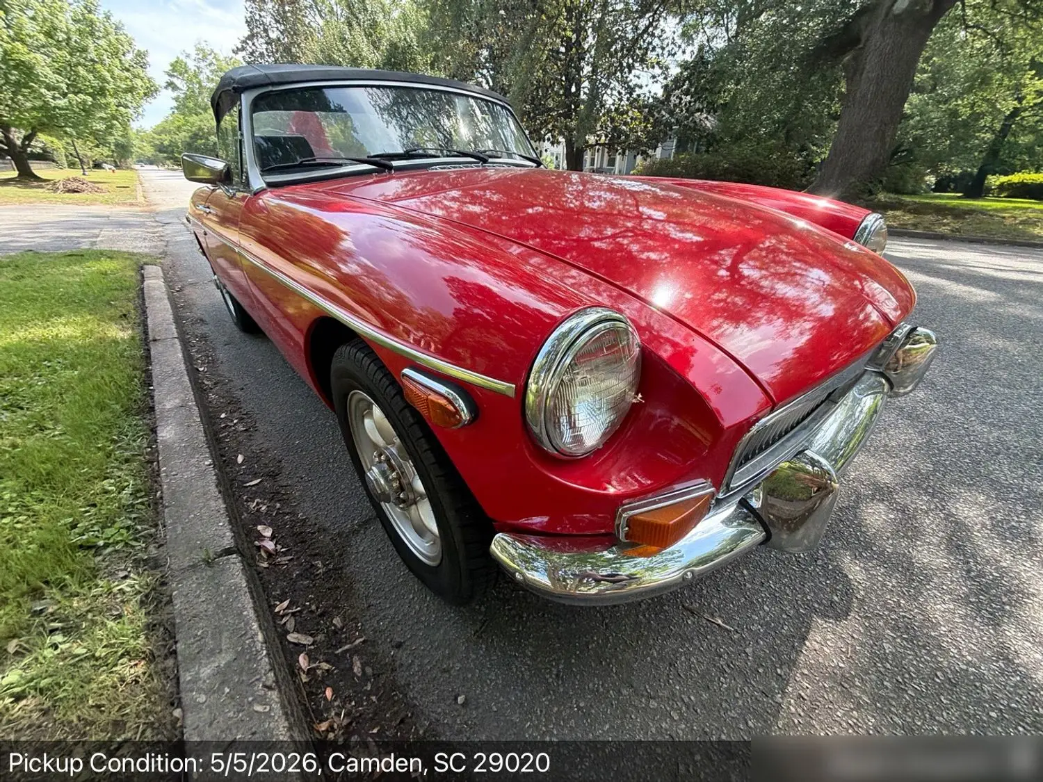 A red vintage MGB convertible roadster at pickup on a tree-lined street in Camden, South Carolina