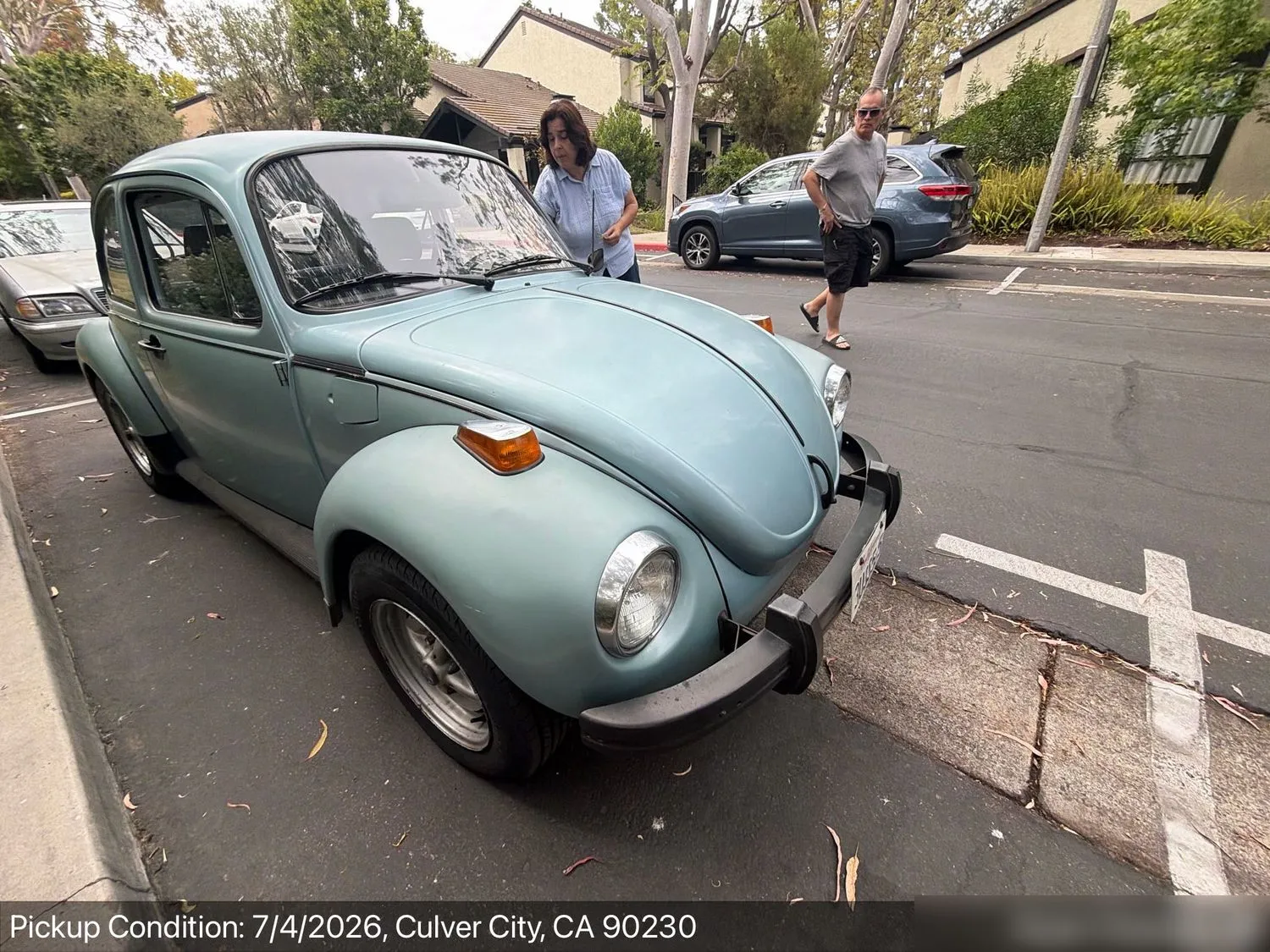 A light blue classic air-cooled Volkswagen Beetle at pickup inspection in a Culver City, California parking lot