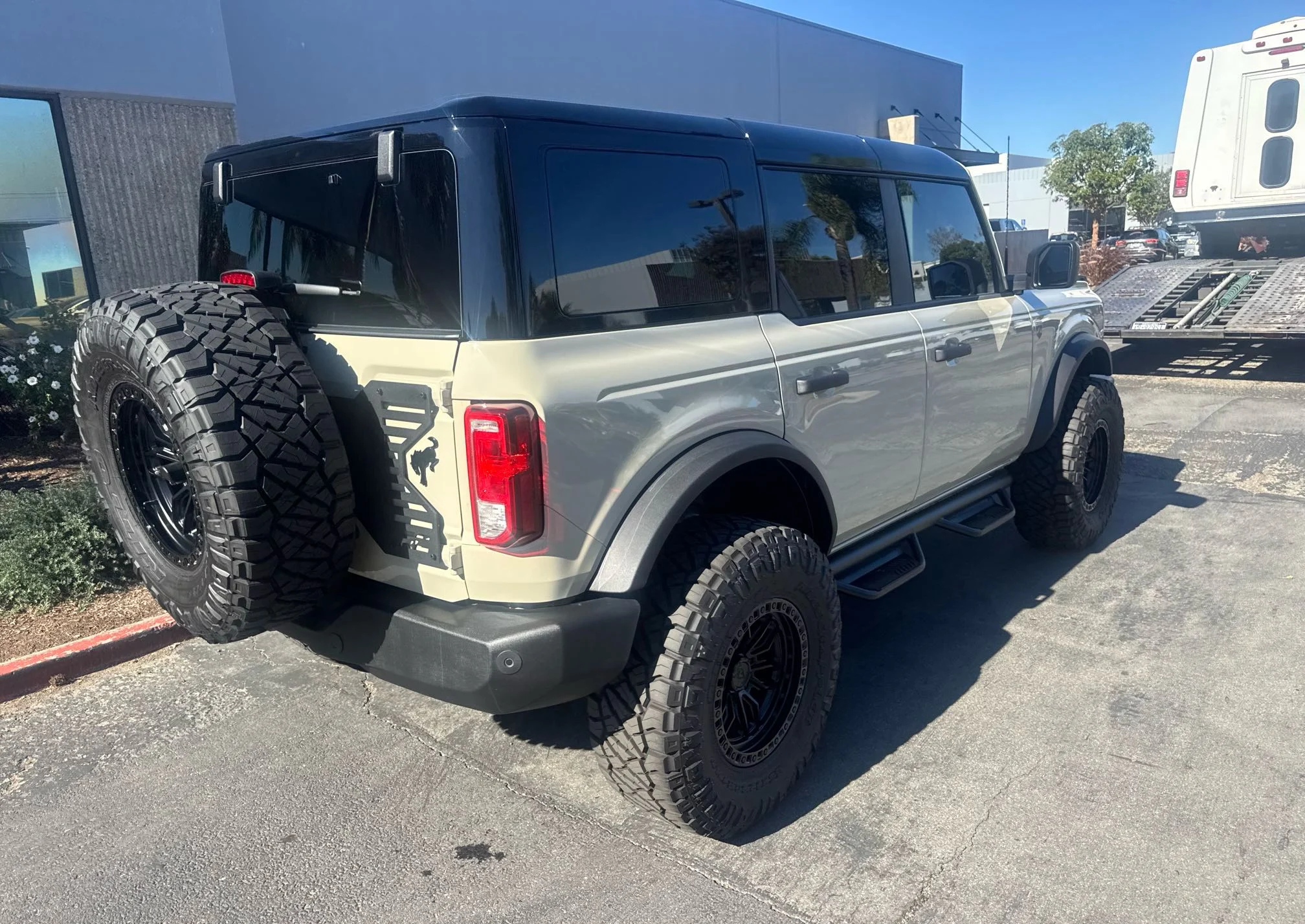 Rear three-quarter view of a custom Ford Bronco with a large rear-mounted spare tire at pickup in Irvine