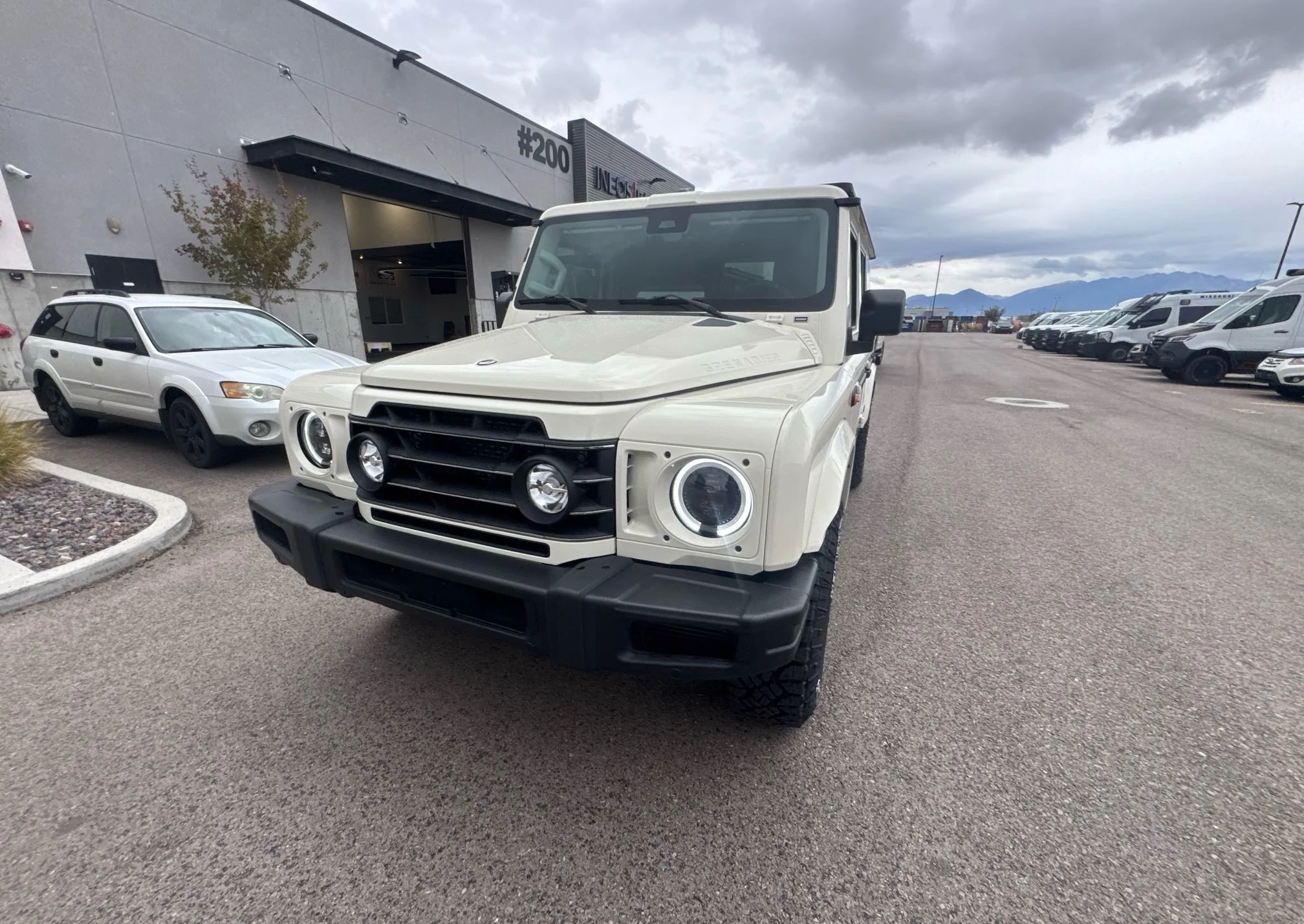 Front three-quarter view of a cream INEOS Grenadier at pickup in West Valley City, Utah