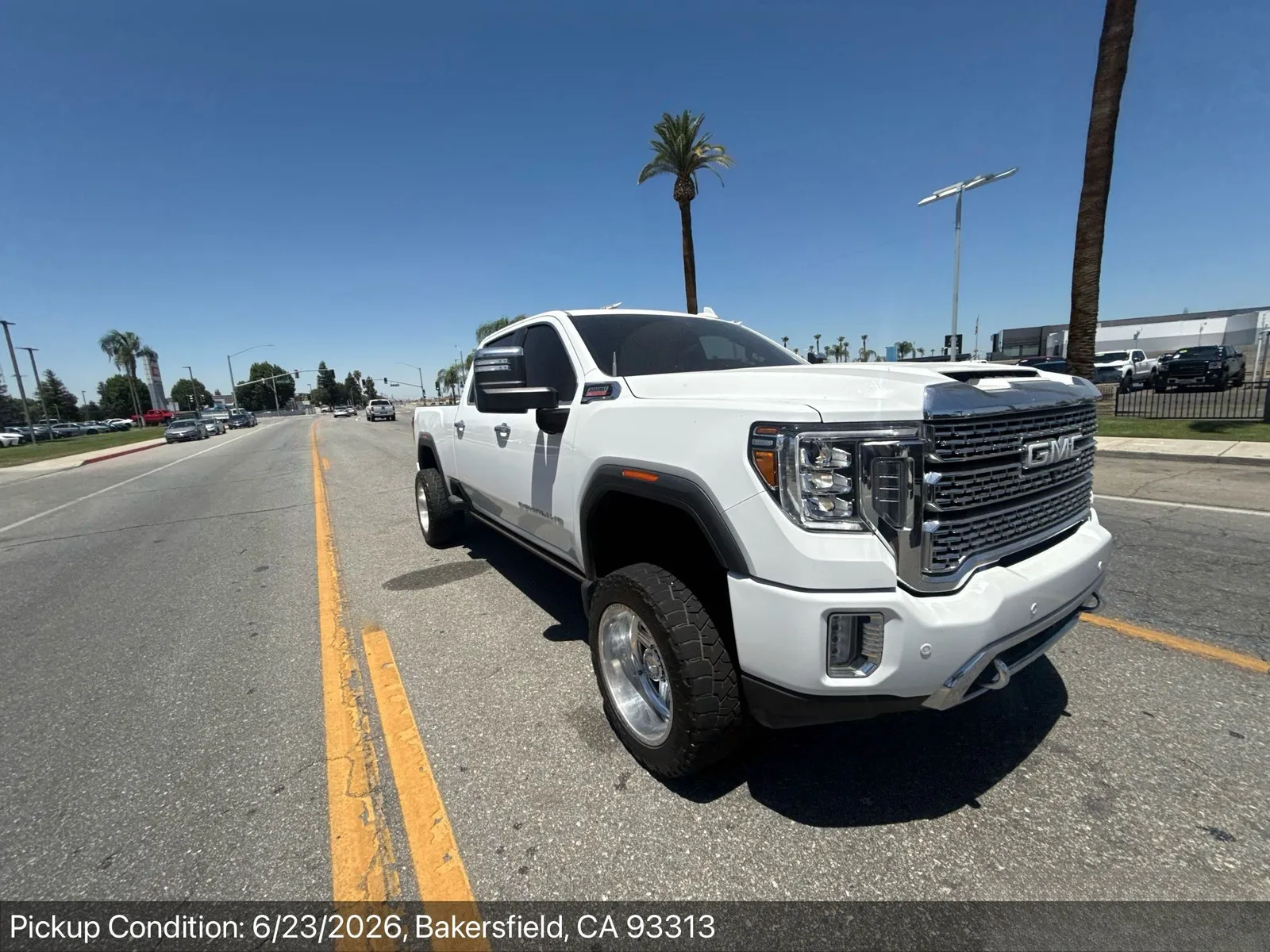 Lifted GMC Sierra Denali HD dually on oversize tires at pickup-condition inspection in Bakersfield, California