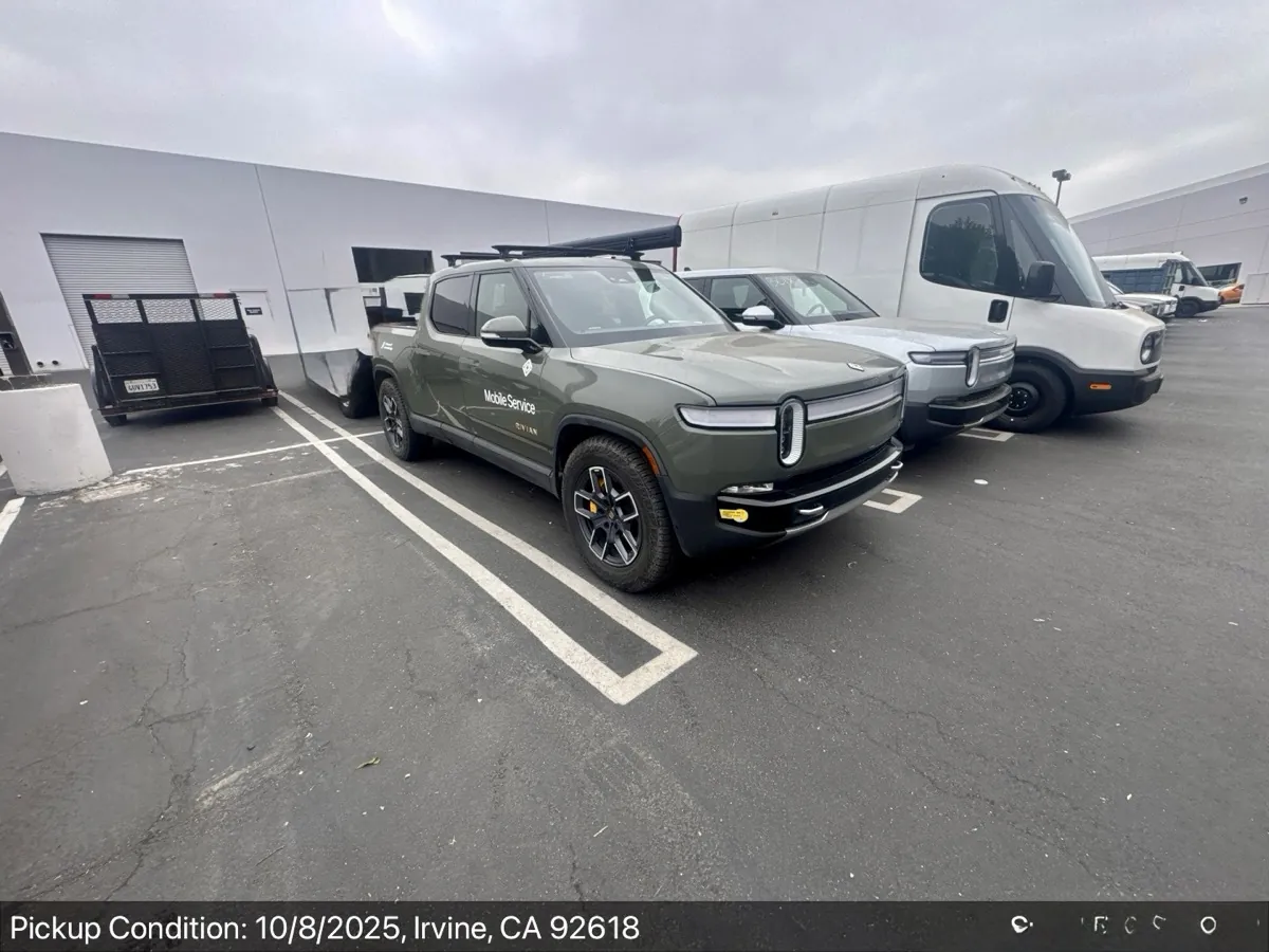Rivian R1T pickup truck and electric Rivian delivery vans at a service depot in Irvine, CA