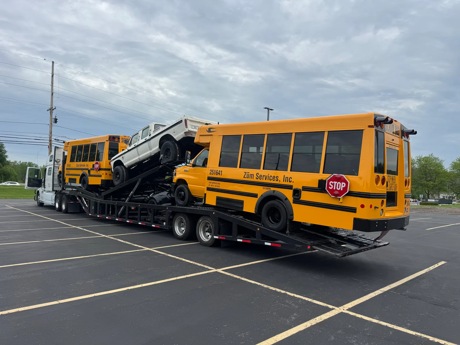 Short yellow school buses loaded on an open carrier for cross-country transport