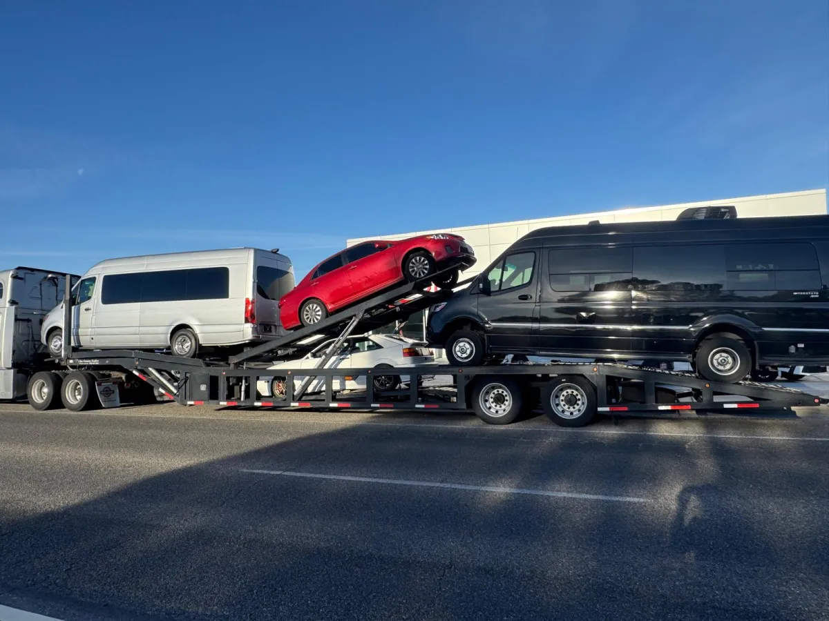 Multiple Sprinter vans and vehicles loaded on an open car carrier